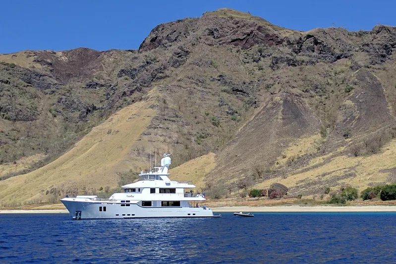  Yacht Photos Pics 2017 Nordhavn 96 yacht anchored near rugged coastal cliffs under clear blue sky.
