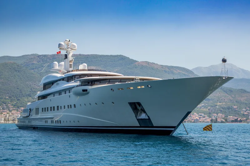 Pelorus Yacht Photos Pics Luxurious 2003 Lurssen Custom yacht on serene waters with mountainous backdrop.