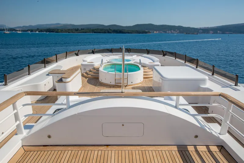 Pelorus Yacht Photos Pics Luxurious 2003 Lurssen Custom yacht deck with jacuzzi, overlooking serene ocean and distant hills.