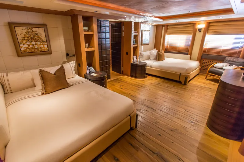 Pelorus Yacht Photos Pics Luxurious yacht bedroom with wooden floors, two beds, and elegant decor, Lurssen Custom 2003.