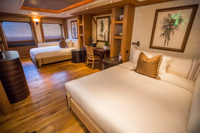 Pelorus Yacht Photos Pics Luxurious yacht bedroom with two beds, wooden flooring, and elegant decor, Lurssen Custom 2003.