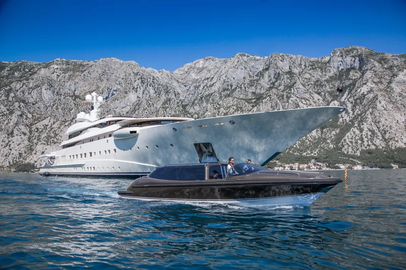 Pelorus Yacht Photos Pics Luxurious 2003 Lurssen Custom yacht with sleek tender, set against stunning mountainous backdrop.