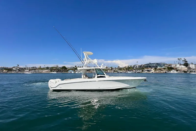 M22 Yacht Photos Pics 2019 Boston Whaler 380 Outrage boat cruising on a sunny day near coastal buildings.
