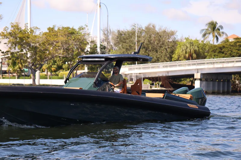 New 2025 Skipper 38 Twin 400 V10 Yacht Photos Pics 2025 Skipper-BSK 38 boat cruising on a sunny day near a bridge and lush greenery.