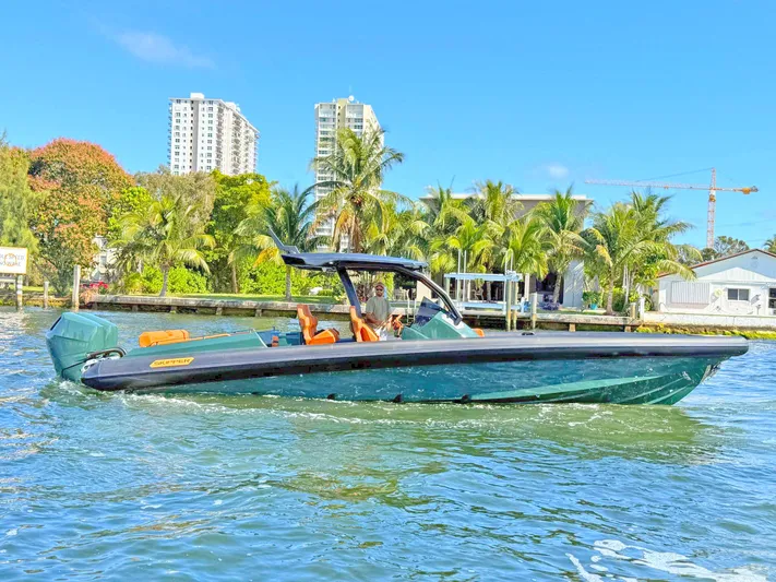 New 2025 Skipper 38 Twin 400 V10 Yacht Photos Pics 2025 Skipper-BSK 38 boat cruising on a sunny day near palm trees and buildings.