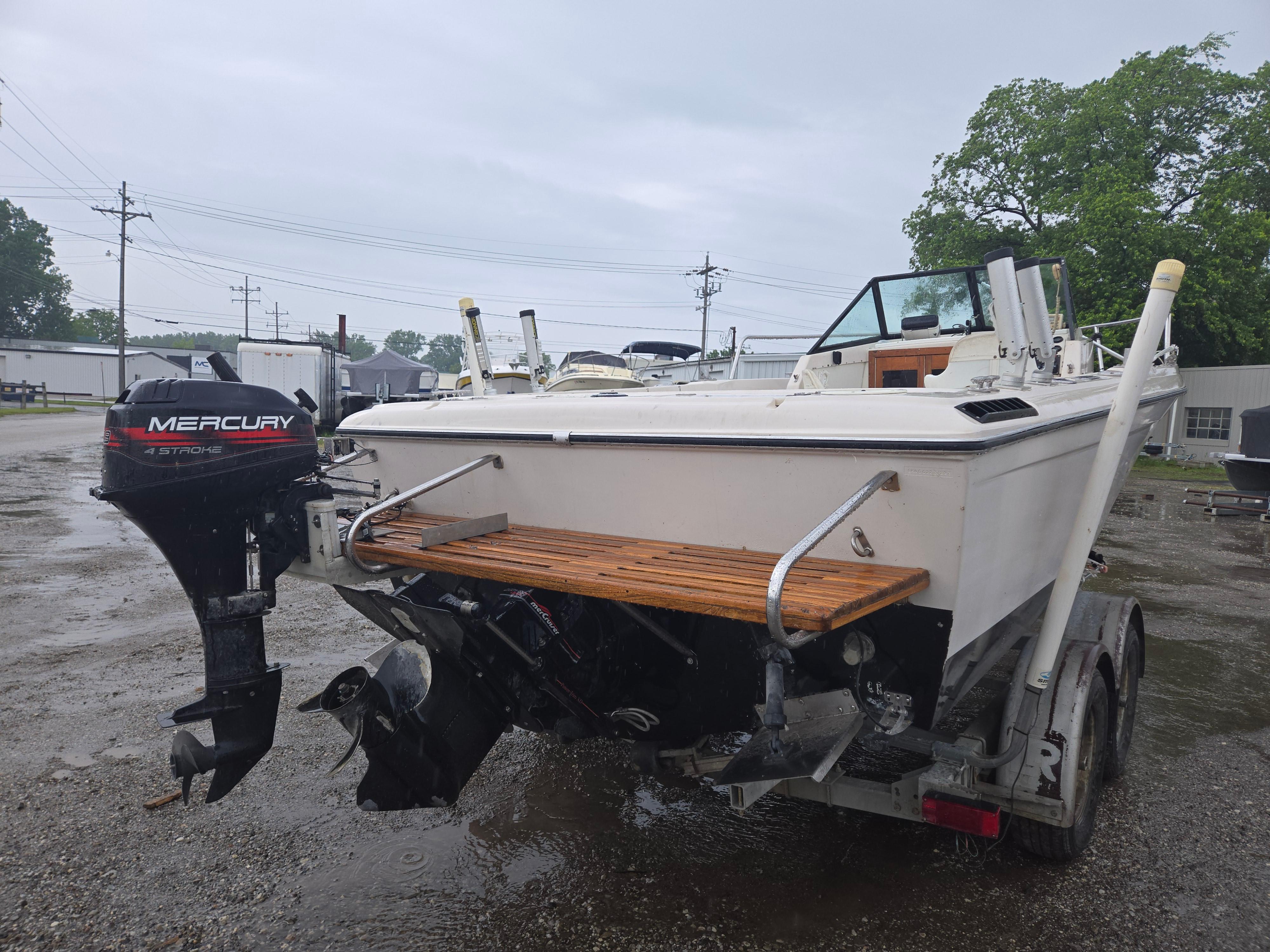 1992 Dixie 21 boat with Mercury outboard motor on a trailer in a parking lot.