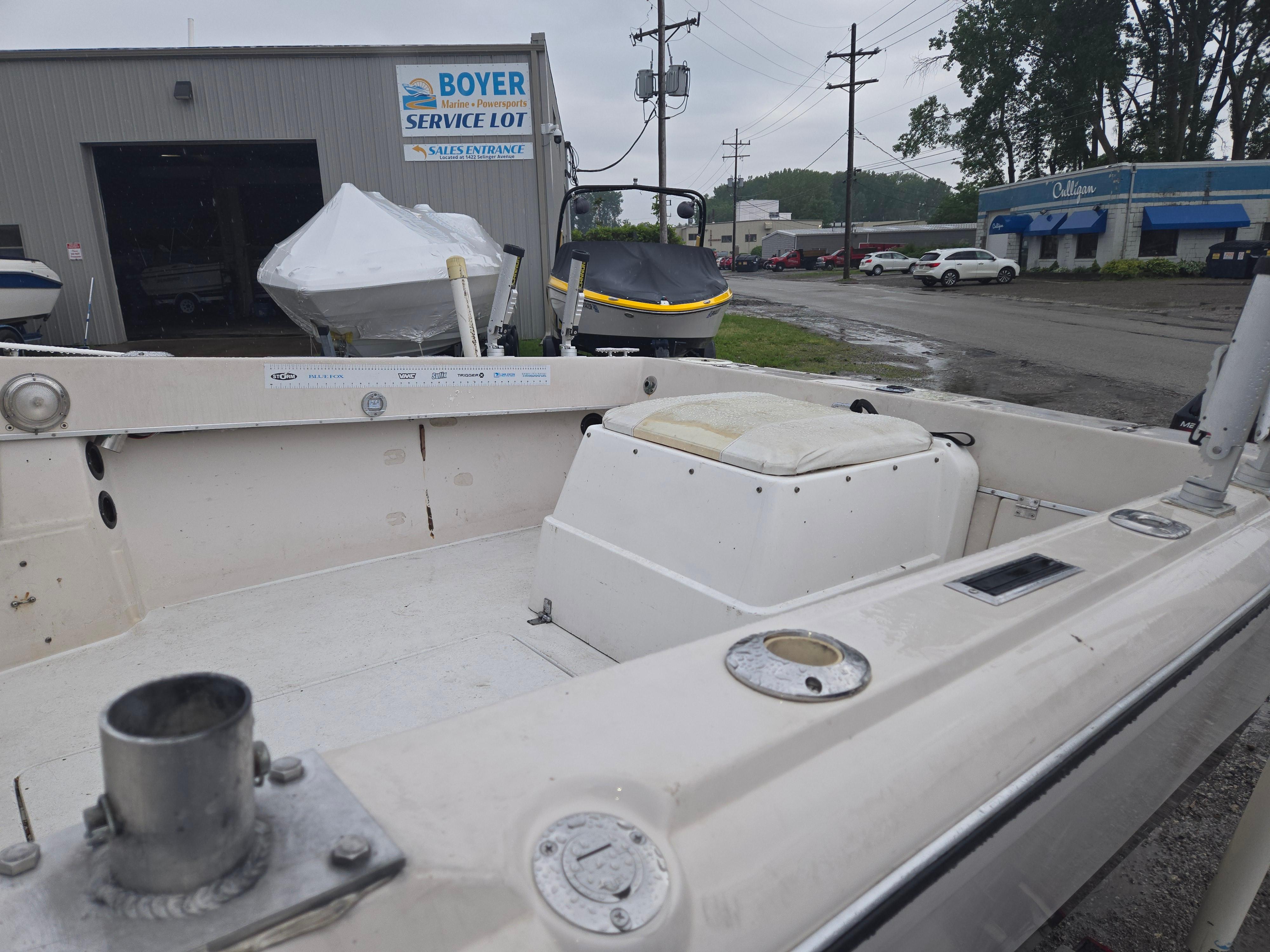 1992 Dixie 21 boat at Boyer service lot, with overcast sky and nearby buildings.