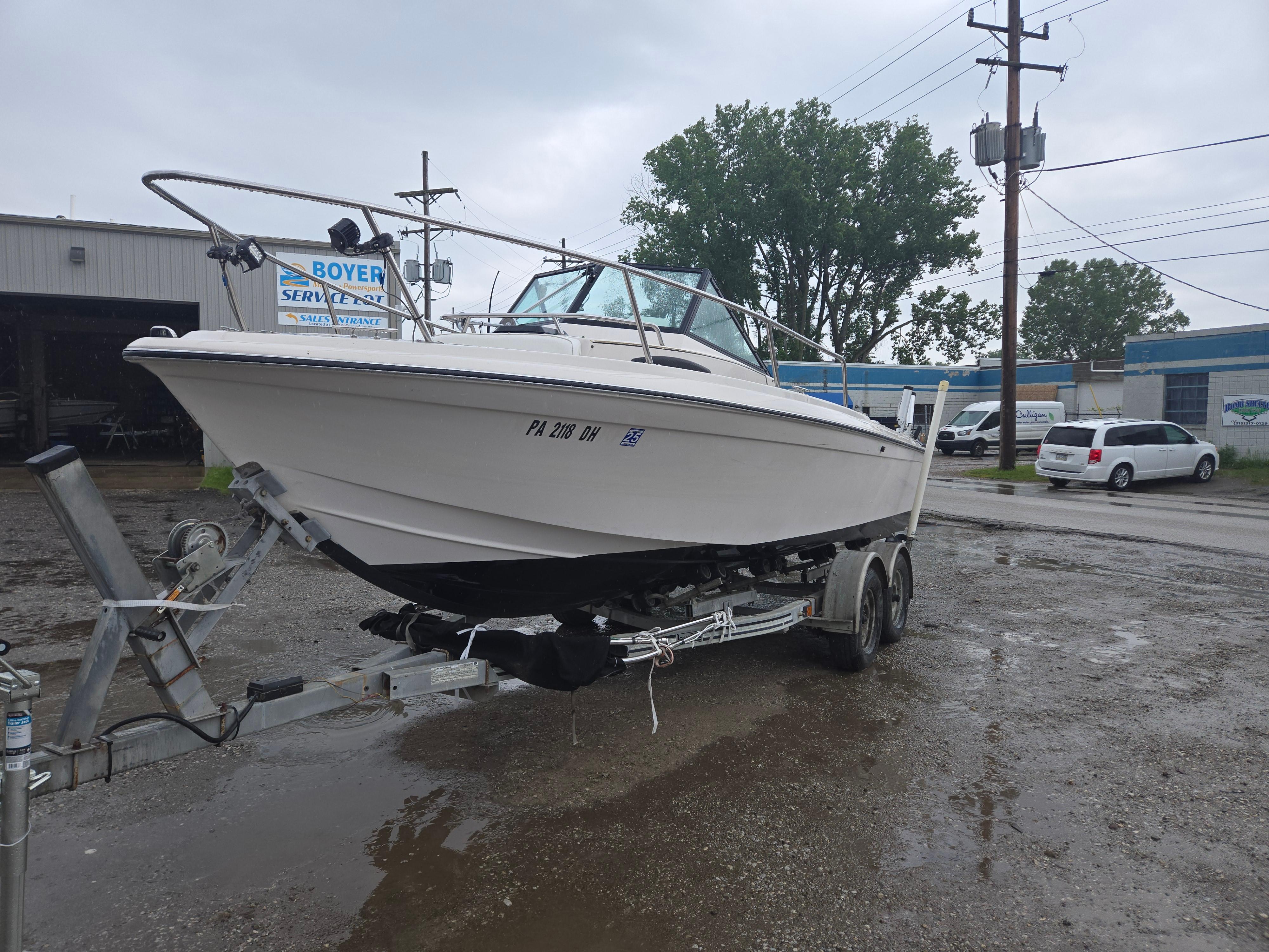 1992 Dixie 21 boat on trailer in a parking lot, overcast sky.