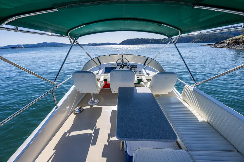 Consequence Free Yacht Photos Pics 2009 Coastal Craft 400 IPS boat interior with seating, table, and steering, under a green canopy.