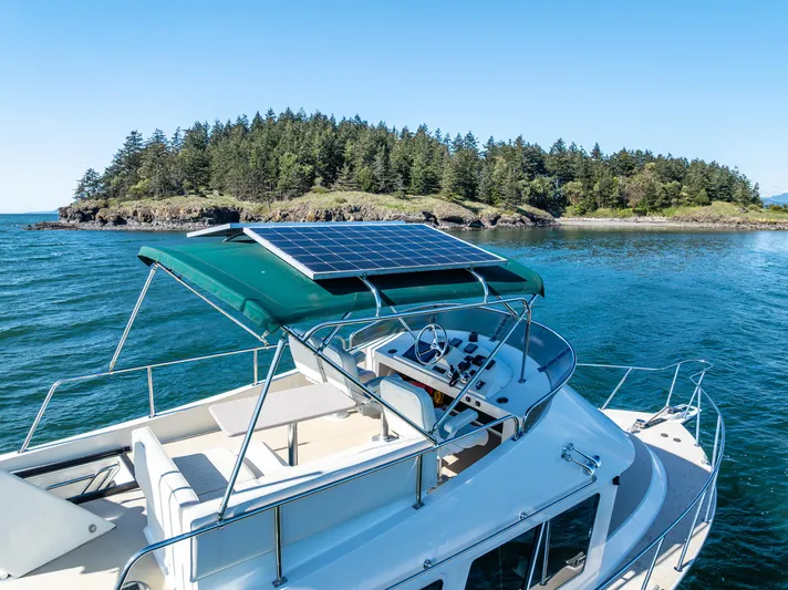 Consequence Free Yacht Photos Pics 2009 Coastal Craft 400 IPS yacht with solar panels, cruising near a forested island.