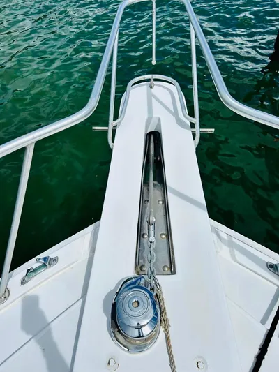  Yacht Photos Pics 1988 Bertram 54' yacht bow with anchor chain and winch over green water.