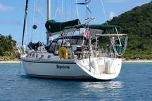Sailboat Caliber 40LRC 1999 anchored near lush island, clear blue water.