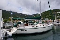 Sailboat Caliber 40LRC 1999 docked in a scenic marina with lush hills.