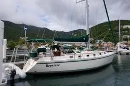 Sailboat Caliber 40LRC 1999 docked in a scenic marina with lush hills.