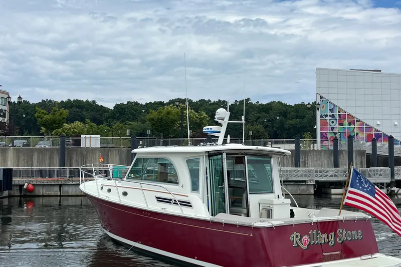 Rolling Stone Yacht Photos Pics 2017 Back Cove 41 boat docked, featuring a red hull and American flag, with colorful building backdrop.