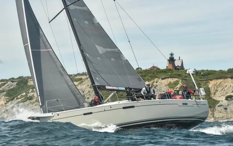 **4806tw Yacht Photos Pics 2017 Dehler 42c sailboat navigating near rocky coastline with lighthouse in background.