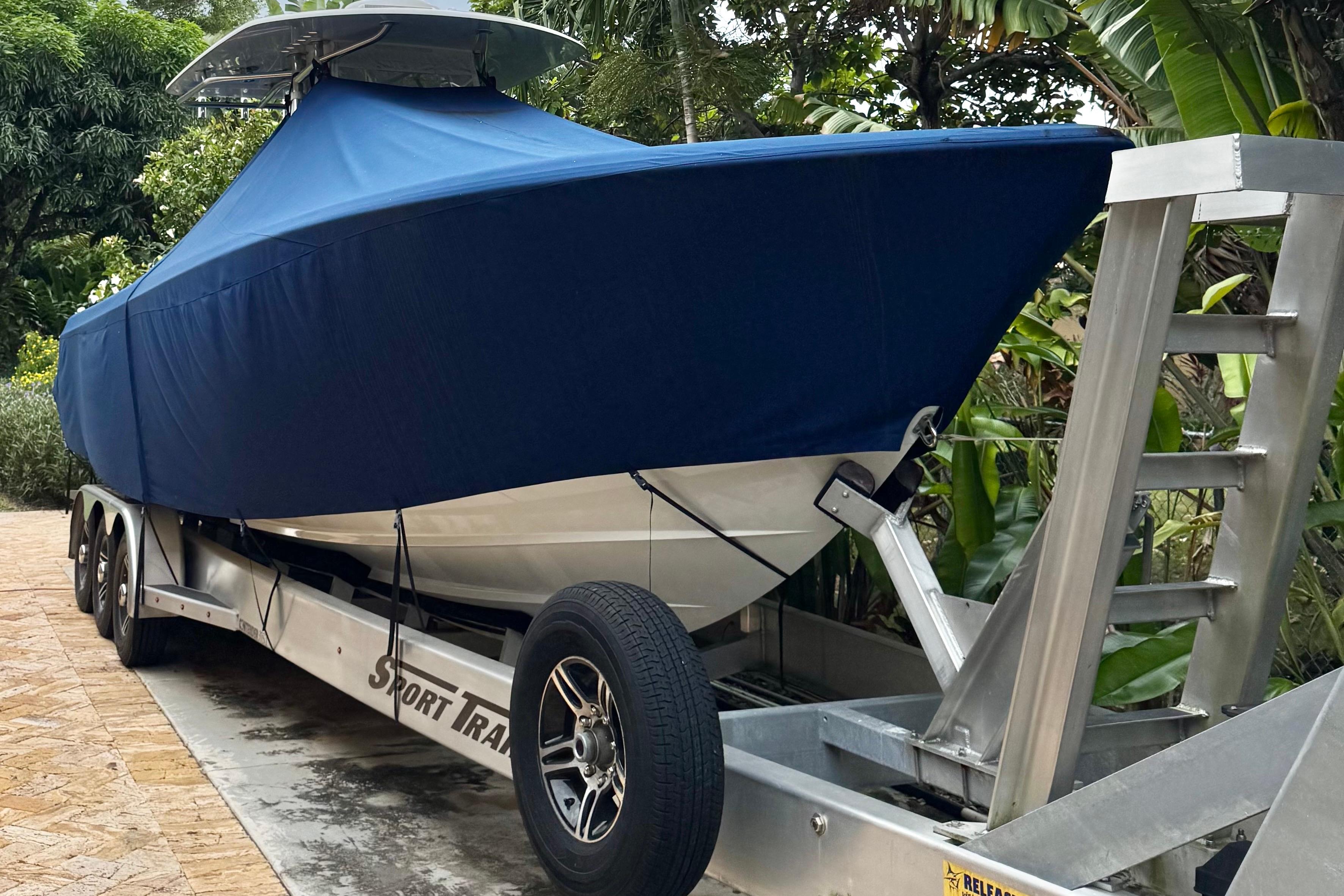 2024 Contender 35 ST boat covered on trailer, surrounded by lush greenery.