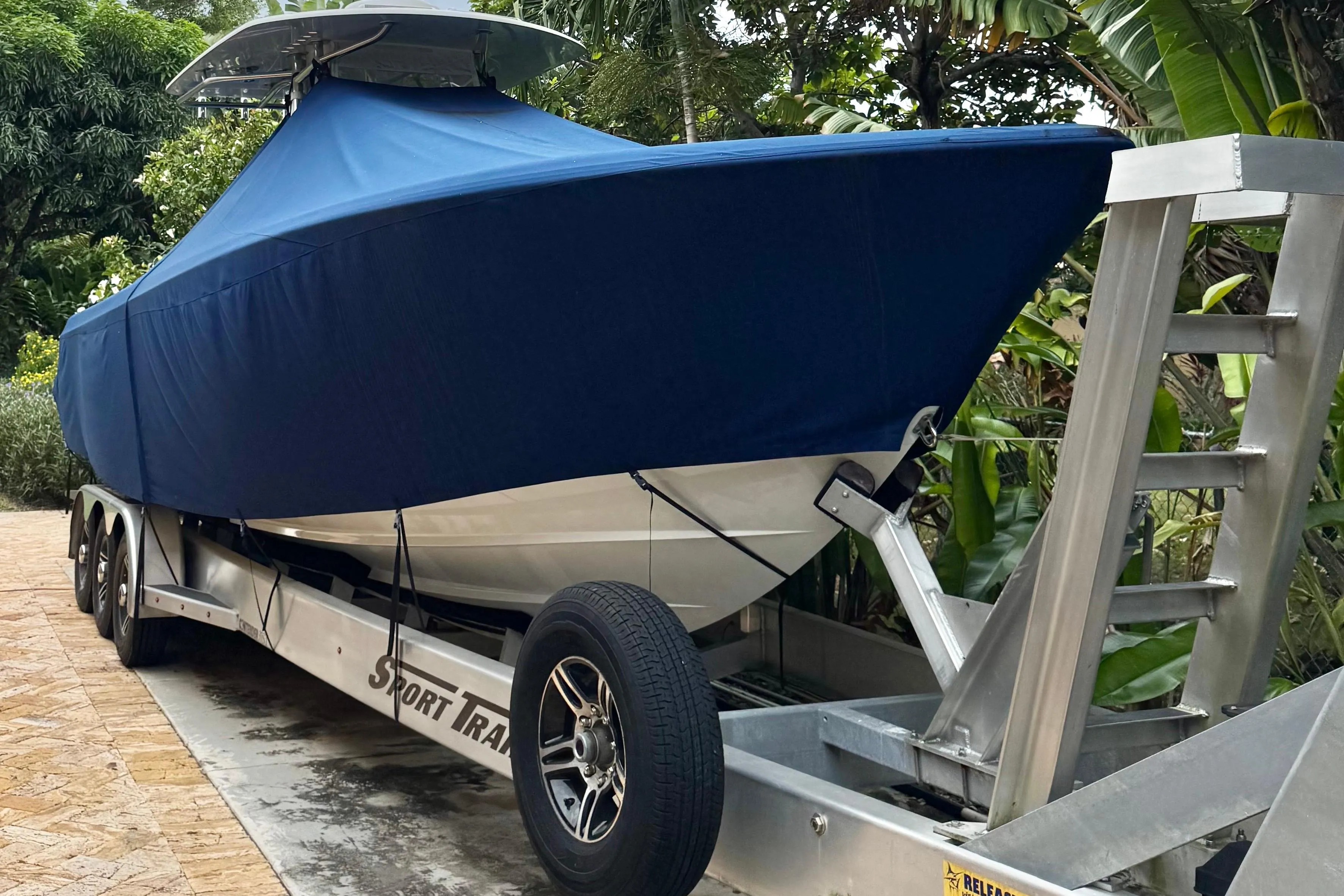 2024 Contender 35 ST boat covered on trailer, surrounded by lush greenery.
