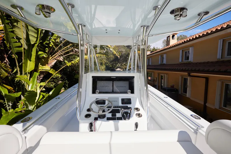  Yacht Photos Pics 2024 Contender 35 ST boat cockpit with Garmin navigation, surrounded by tropical foliage.