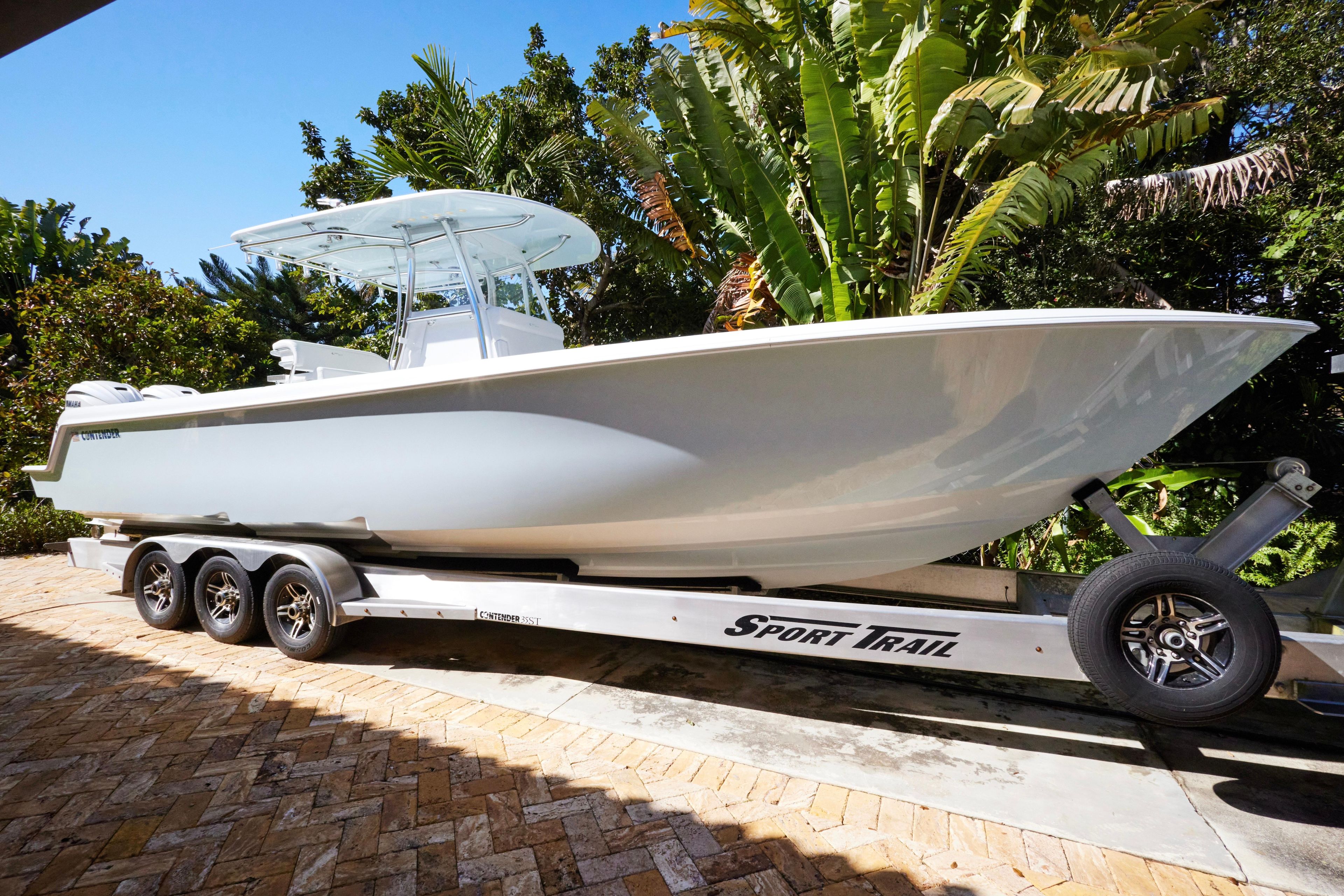 2024 Contender 35 ST boat on trailer, surrounded by lush greenery.