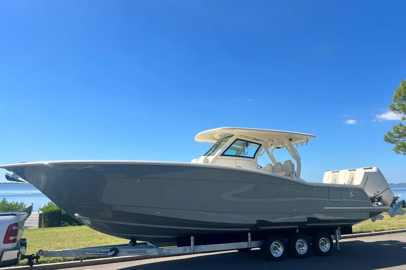  Yacht Photos Pics 2026 Scout 357 LXF boat on trailer, parked near a scenic waterfront.