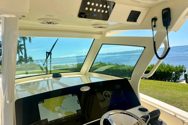  Yacht Photos Pics Interior view of 2026 Scout 357 LXF boat with navigation system and scenic waterfront.