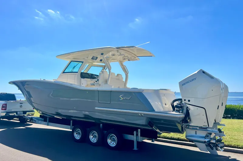  Yacht Photos Pics 2026 Scout 357 LXF boat on trailer with Mercury engines, parked by the water.