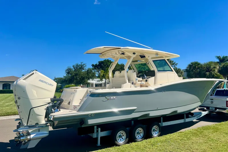  Yacht Photos Pics 2026 Scout 357 LXF boat on trailer, featuring Mercury engines, parked outdoors under clear blue sky.