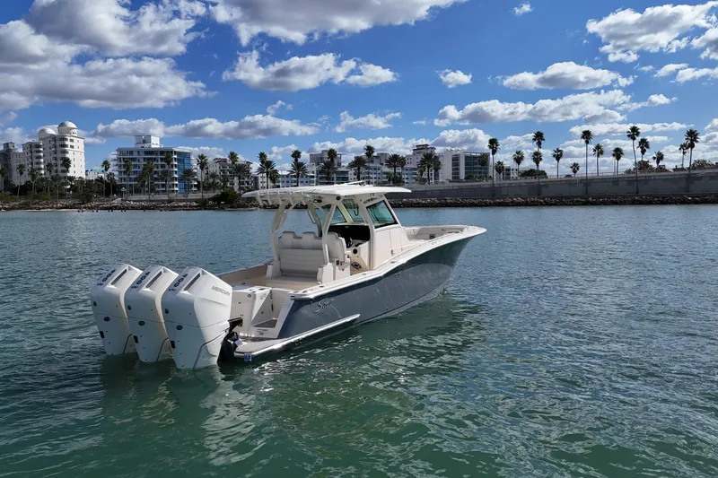  Yacht Photos Pics 2026 Scout 357 LXF boat on water, cityscape and palm trees in background.