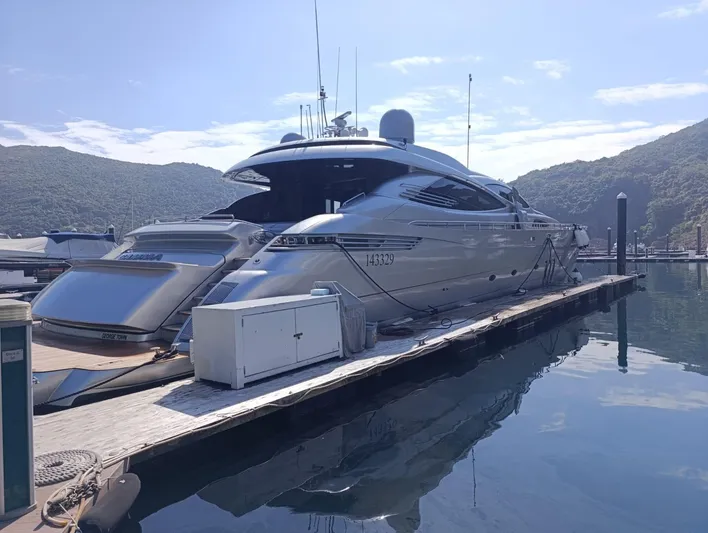 Gamma Yacht Photos Pics Luxury 2007 Pershing 115 yacht docked at marina, surrounded by scenic hills and calm water.