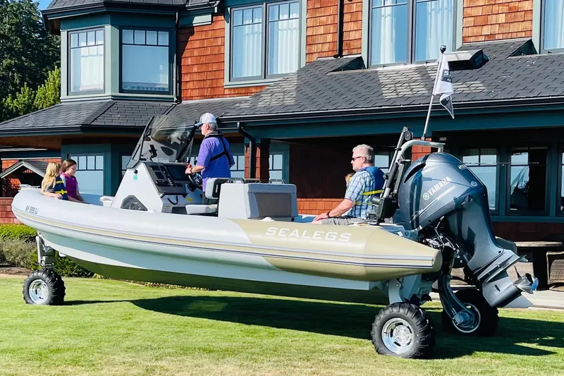  Yacht Photos Pics 2022 Sealegs 7.5M amphibious boat on grass, near a house, with passengers onboard.