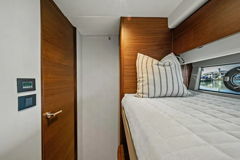 R&r Yacht Photos Pics 2023 Princess F50 yacht interior cabin with bed, striped pillow, and wooden door.