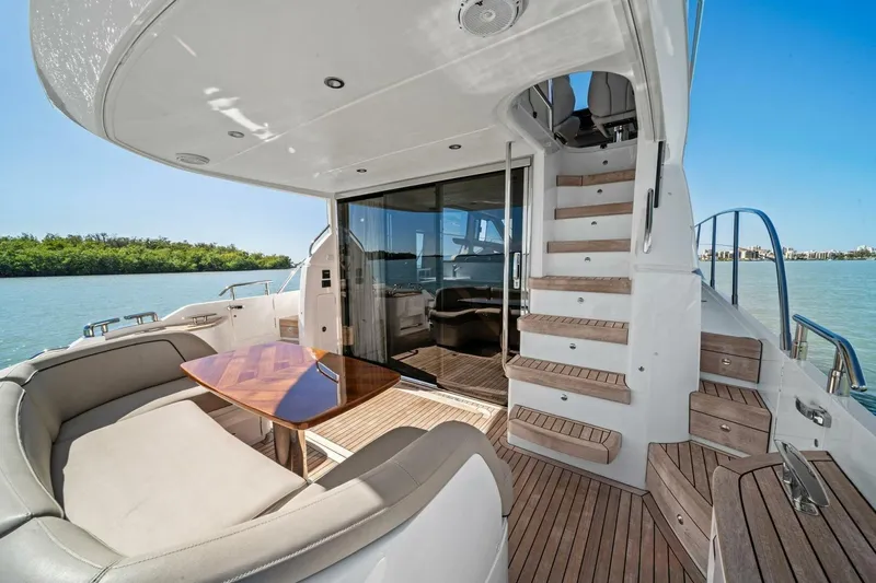 R&r Yacht Photos Pics Luxurious 2023 Princess F50 yacht deck with seating, table, and stairs, overlooking serene waters.