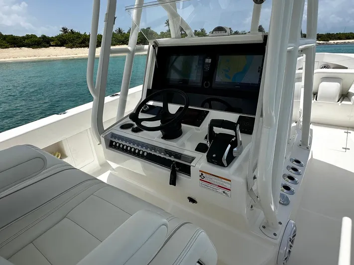  Yacht Photos Pics 2024 SeaVee 340Z boat cockpit with modern controls, steering wheel, and navigation screens near a beach.