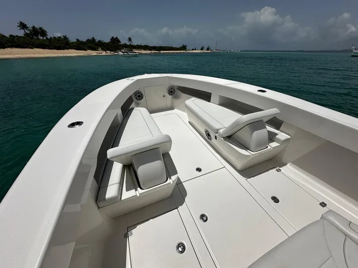  Yacht Photos Pics 2024 SeaVee 340Z boat with spacious seating, cruising on clear turquoise waters near a sandy beach.
