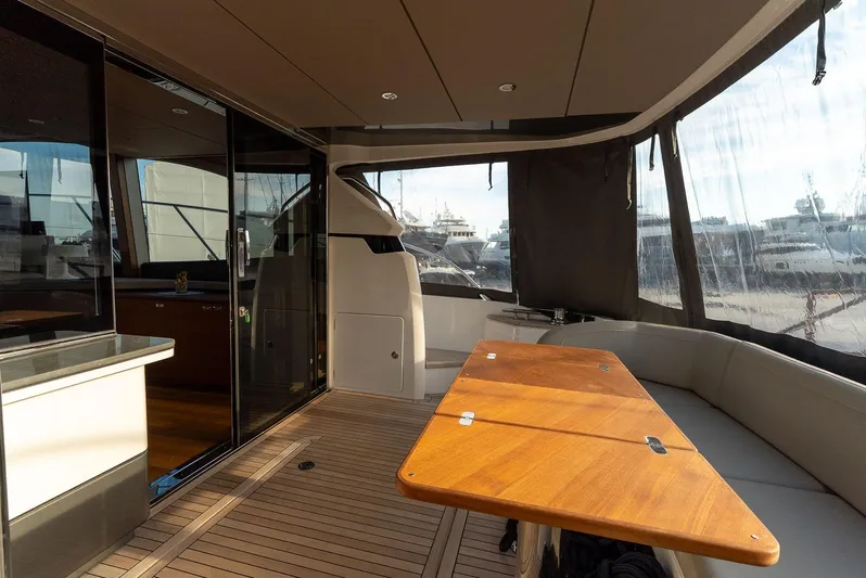  Yacht Photos Pics Luxurious 2024 Princess F55 yacht interior with wooden table and seating area.