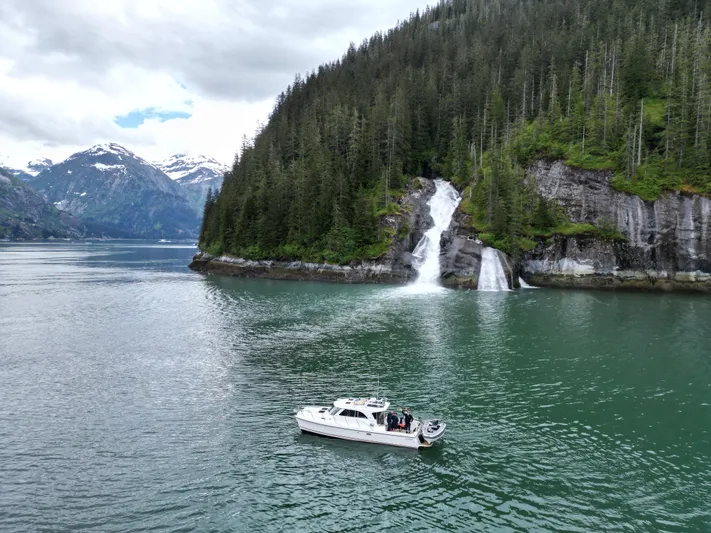  Yacht Photos Pics Boat on serene lake with waterfall and forested mountains, Aspen C100, 2026 model.