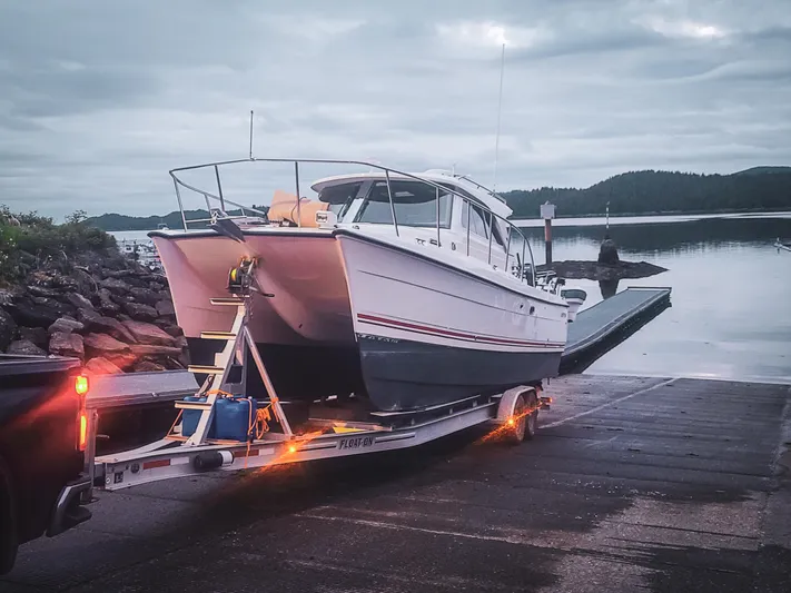  Yacht Photos Pics 2026 Aspen C100 boat on trailer at lakeside ramp during overcast day.