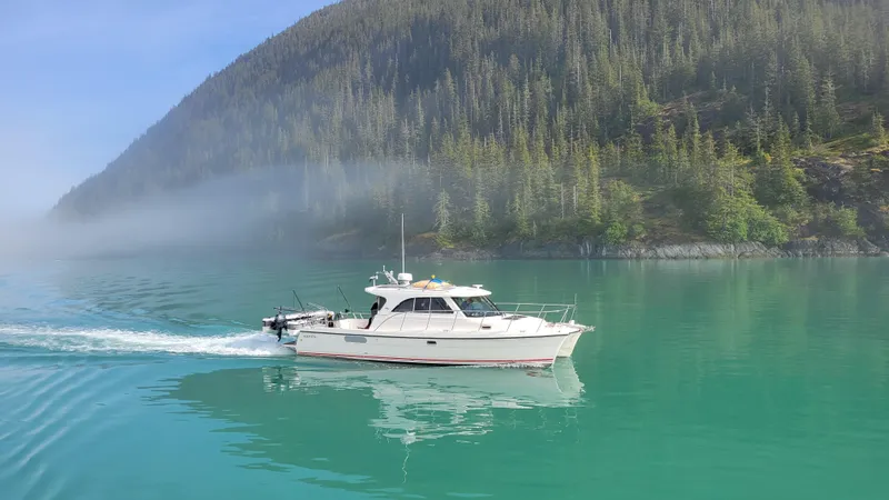  Yacht Photos Pics Aspen C100 boat cruising on serene turquoise water with forested hills in the background.