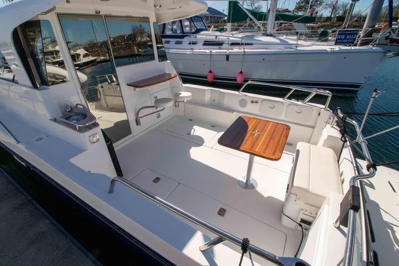  Yacht Photos Pics 2026 Aspen C100 boat with spacious deck, wooden table, and seating in a marina setting.