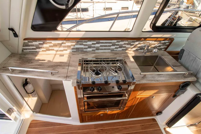  Yacht Photos Pics Modern kitchen in 2026 Aspen C100 boat with stove, sink, and stylish backsplash.