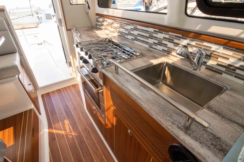  Yacht Photos Pics Modern kitchen in 2026 Aspen C100 boat with stove, sink, and wood flooring.
