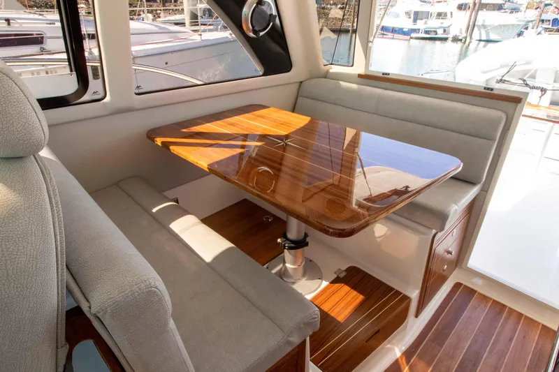  Yacht Photos Pics Interior of 2026 Aspen C100 boat with wooden table and cushioned seating.