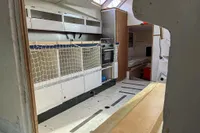 Interior of a 1999 Custom Open 50 sailboat, featuring a compact kitchen and sleeping area.