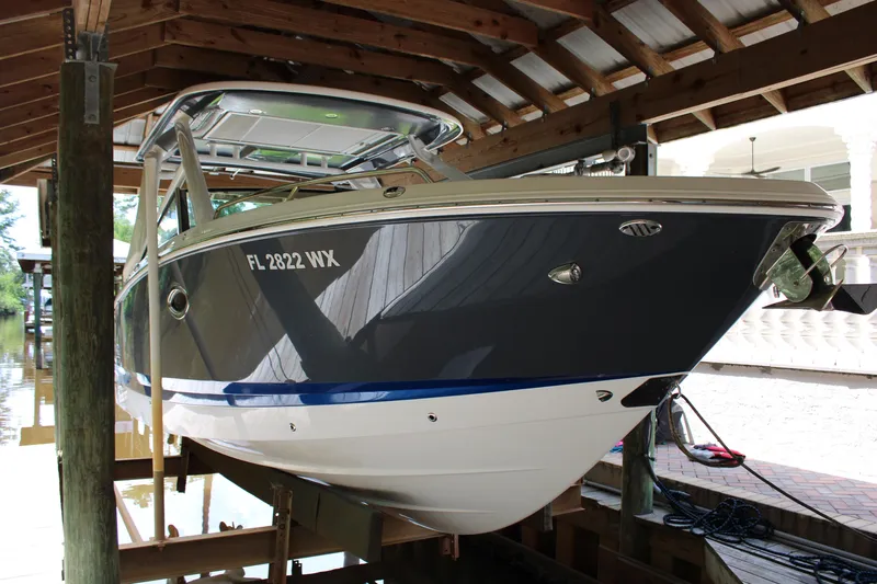  Yacht Photos Pics 2021 Chaparral 280 OSX boat docked under a wooden shelter.