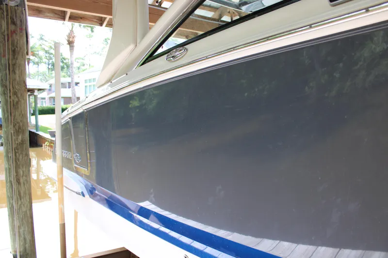  Yacht Photos Pics 2021 Chaparral 280 OSX boat docked under a wooden shelter.