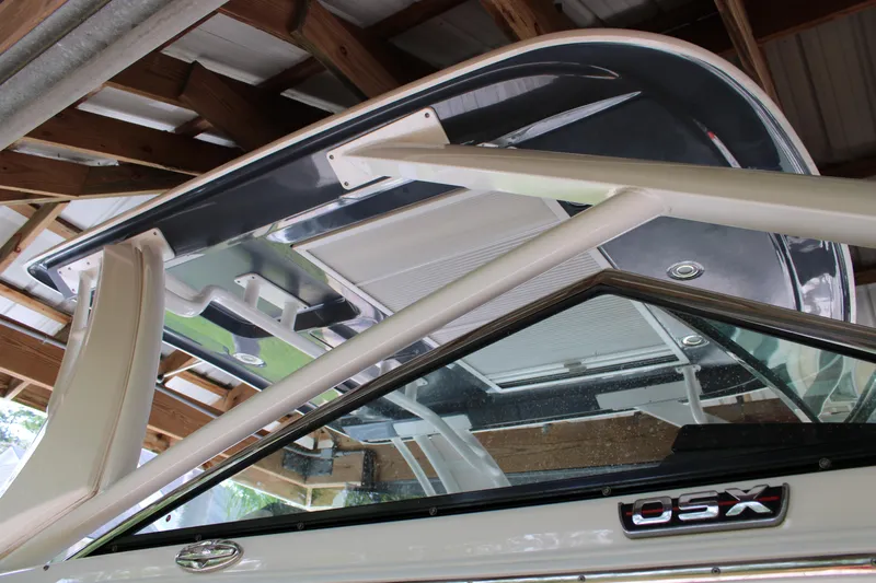  Yacht Photos Pics 2021 Chaparral 280 OSX boat under a wooden shelter, showcasing its sleek design.