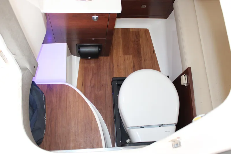  Yacht Photos Pics 2021 Chaparral 280 OSX boat interior with wooden flooring and compact toilet.