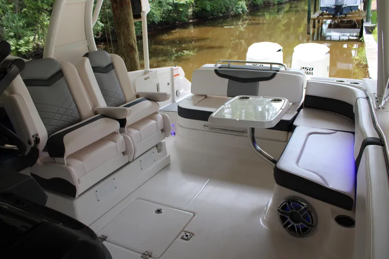  Yacht Photos Pics 2021 Chaparral 280 OSX boat interior with seating and table, docked by a wooded area.