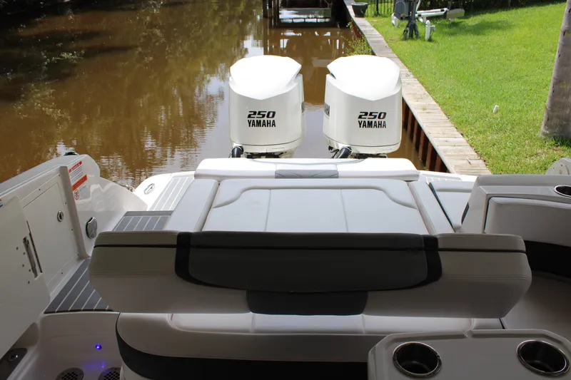  Yacht Photos Pics 2021 Chaparral 280 OSX boat with twin Yamaha 250 engines docked by a grassy area.